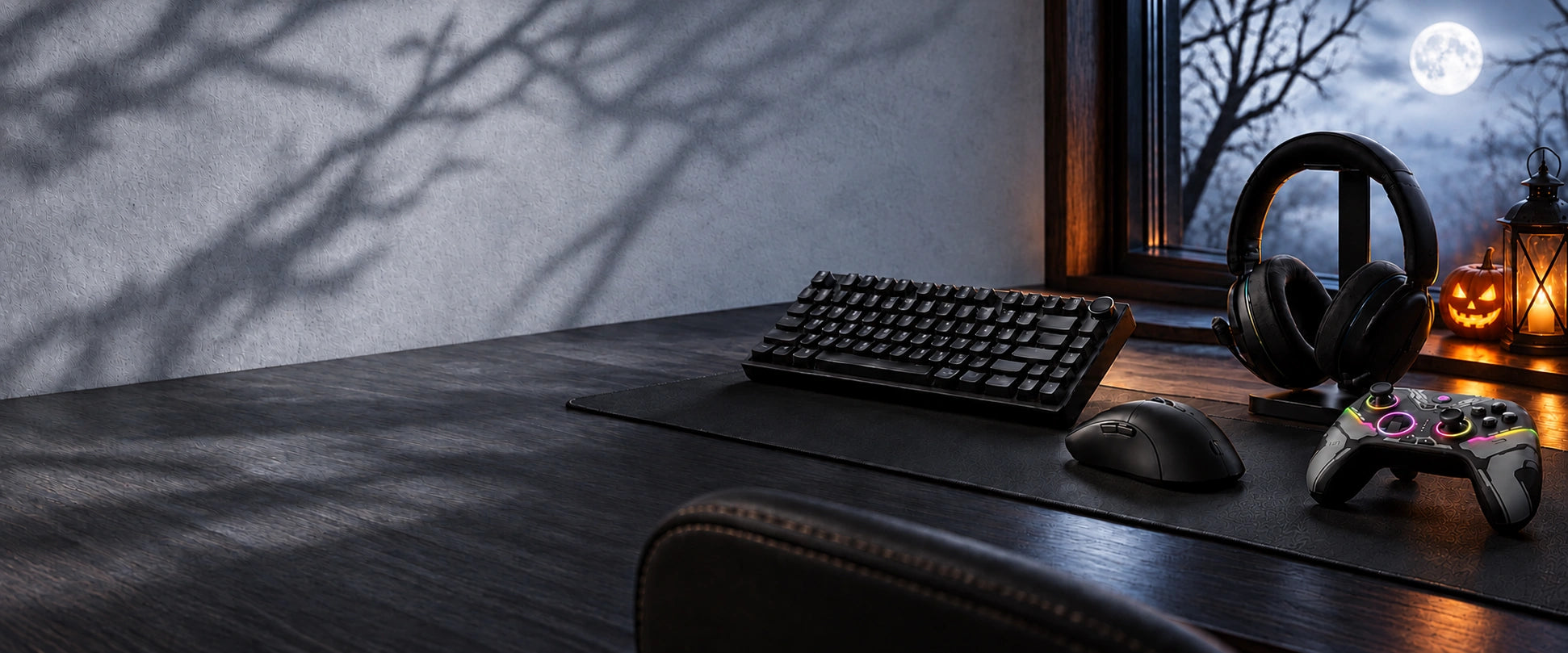 Gaming keyboard, mouse, headset and controller beside a moonlit Halloween window, pumpkin and lantern